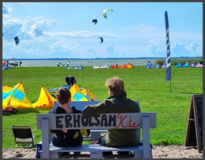 2 Personen schauen beim Kitesurfen zu. Im Hintergrund wird auf dem Saaler Bodden gekitet.