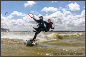 Kitessurfer auf dem Saaler Bodden mit einem Mädchen auf dem Rücken.